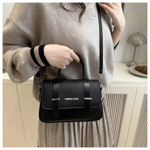 Détail du sac boîte noir avec texture litchi et bijoux argentés en décor de vie