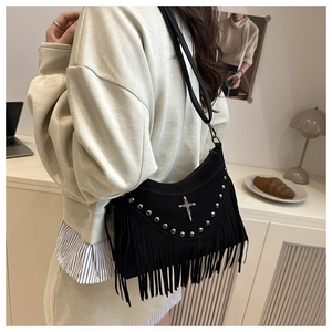 Detail of a black studded shoulder bag with long fringes and silver cross pendant