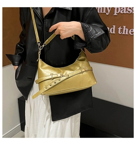 Détail d'un sac demi-lune doré brillant avec lanières croisées et boucle en métal