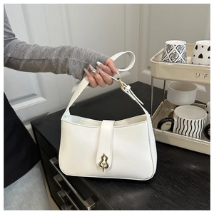 Detail of white matte leather underarm bag with unique gold gourd-shaped clasp and strap