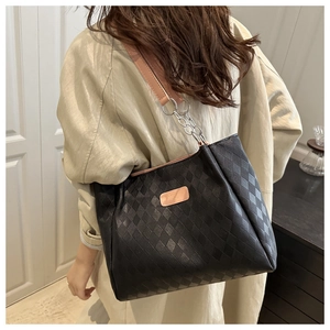 Detail of black quilted tote bag with pink shoulder strap and silver metal chain links