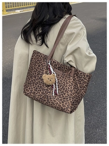 Foto all'aperto di una borsa tote leopardata grande con ciondolo a orsetto su cappotto
