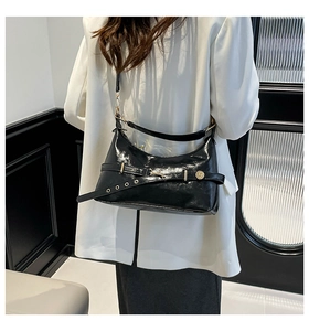 Vue détaillée du sac à bandoulière en cuir brillant noir avec boucle dorée et ceinture