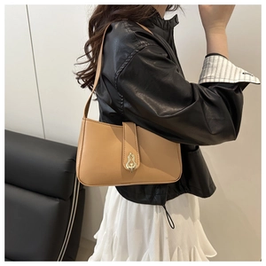 Detail of camel leather baguette bag with gold metal buckle shown on a model