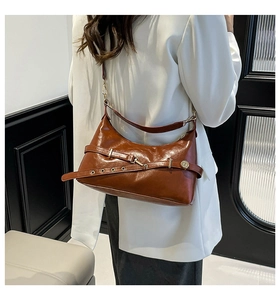 Brown vintage crescent hobo bag with gold hardware worn as a stylish shoulder bag