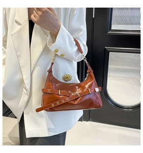 Brown vintage style leather shoulder bag with gold buckle detail worn with white suit