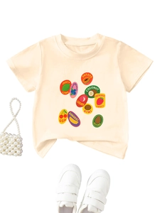 T-shirt crème enfant avec motifs de fruits, mini sac perlé et baskets blanches posés à plat
