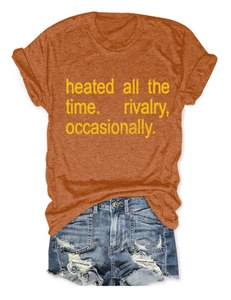 Flat lay of women's orange crewneck T-shirt with text and ripped blue denim shorts