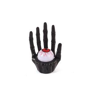 Halloween skeletal hand holding a realistic white eyeball ornament for spooky party decor