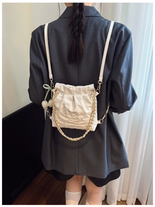 Close-up of beige quilted backpack with gold chain detail and tulip flower pendant