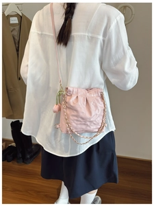 Detail of light pink quilted crossbody bag with tulip charm and elegant drawstring texture