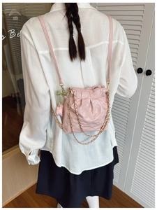 Rear view of pink quilted drawstring bucket bag with gold chain strap on a model