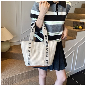 Détail du cabas en paille beige avec sangles en toile et base en cuir marron