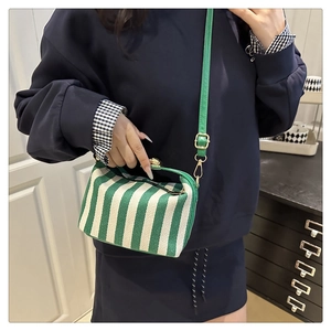 Detail of green striped canvas doctor bag featuring a golden metal clasp and leather strap