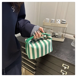 Detailed close-up of green and white striped canvas tote bag with premium leather handles