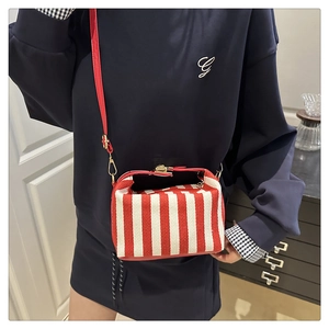 Detail of red and white striped tote bag with leather strap and metal buckle closure