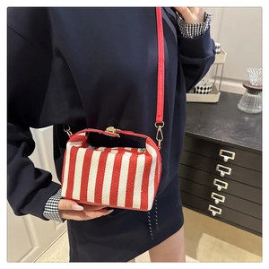 Close-up of red and white striped canvas handbag with golden metal hardware detail