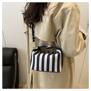 Person wearing striped canvas tote bag with leather straps on a khaki trench coat