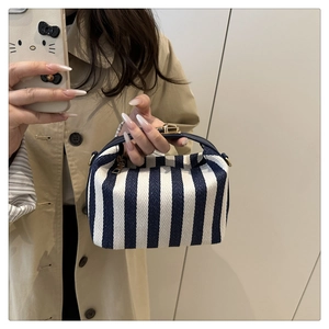 Blue striped canvas pillow bag with navy leather handles and gold metal lock shown with model