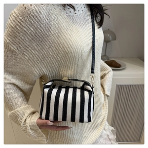Detail of black and white striped canvas crossbody bag with woven texture and metal clasp