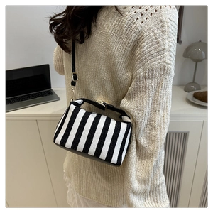 Lifestyle shot of striped canvas mini bag held by a person in a modern office setting