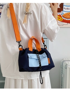 Detail shot of the color-block nylon crossbody bag with orange straps and blue pocket
