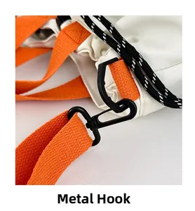 Detail of durable black metal swivel hook and bright orange nylon strap on a white bag