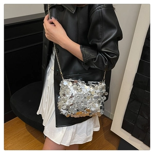Detail of silver sequin crossbody bag with gold chain strap on a model wearing black