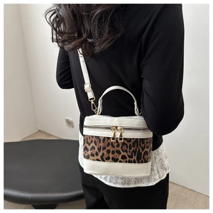 Detail of a cylinder bucket bag featuring leopard print patchwork and a golden zipper