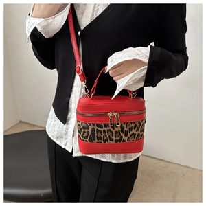 Detail der roten Beuteltasche mit Leopardenmuster und goldenen Doppelreißverschlüssen