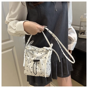 Detail of white quilted bubble fabric tote bag with black bow print and drawstring closure