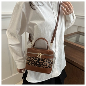 Brown leopard print patchwork makeup bag shown on a model in a minimalist modern setting