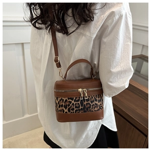 Detail view of leopard print bucket bag with brown leather trim and gold hardware