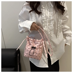 Detail of pink quilted bucket bag featuring black bow patterns and adjustable drawstring