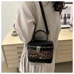 Detail of leopard print cylinder bag with gold zippers and black leather texture