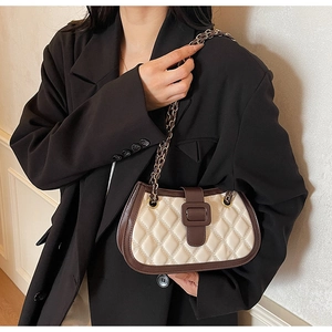 Detail of quilted beige leather shoulder bag with dark brown trim and gold chain strap