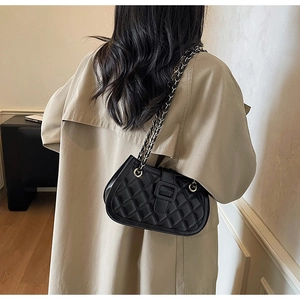 Detail of black quilted chain shoulder bag shown on model for size and style reference