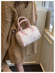 Detail of white cylinder bucket bag with pink handles and cartoon character patterns
