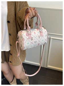 Detail of a creamy cylinder bucket bag featuring cute cartoon patterns and pleated texture