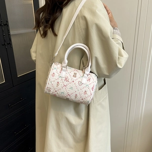 White cartoon print bucket bag with handle and shoulder strap shown on a model