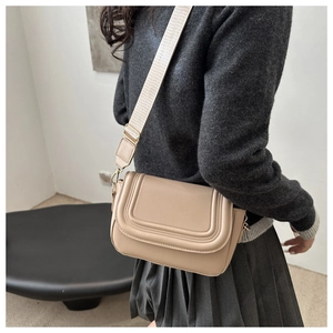Vista laterale della borsa beige con tracolla larga su modella che mostra il profilo