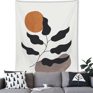 Close-up of minimalist botanical tapestry featuring orange sun and black leaves on a white wall