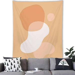 Abstract geometric tapestry with orange and pink tones hung above a grey sofa