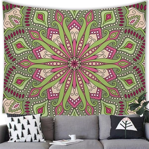 Bohemian mandala tapestry with green and pink patterns on a wall behind a sofa