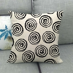 Linen cushion cover with black spiral patterns on a grey sofa in a minimalist living room