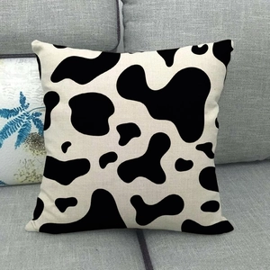 Close-up of black and white cow print linen pillowcase texture on a grey fabric sofa