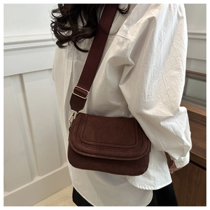 Detail of dark brown matte flap bag with circular stitching and adjustable wide strap