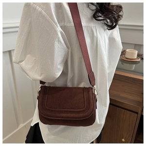 Detail of dark brown matte suede crossbody bag with wide strap and gold hooks on shoulder