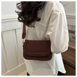 Detail of brown suede crossbody bag with decorative stitching on a model side view