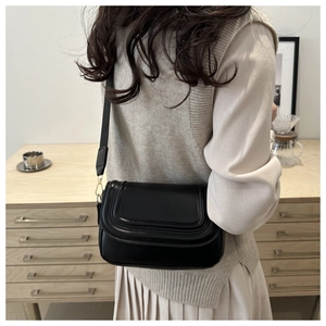 Modella indossa borsa a sella nera in ecopelle con cuciture curve raffinate